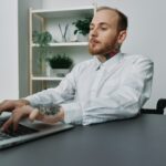 A man in a wheelchair a businessman with tattoos in the office works at a laptop, integration into